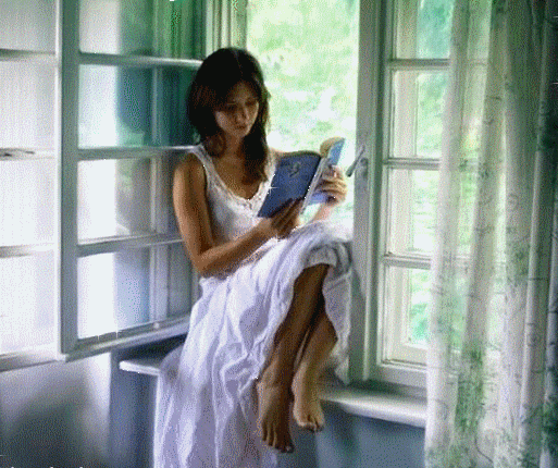 Девушка читает книгу сидя на окне